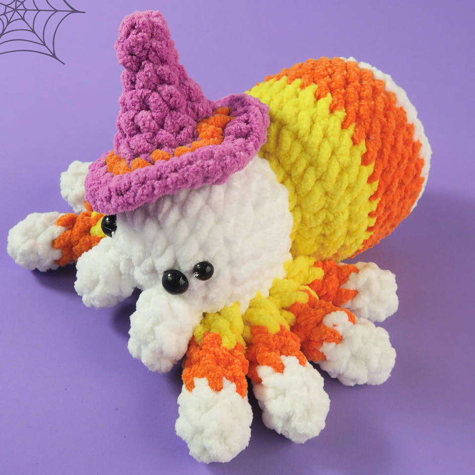 Crocheted Spooky Candy Corn Spider with candy corn pattern and witch hat on a purple background