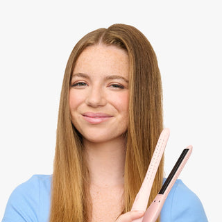 Woman holding a hair straightener against a light background