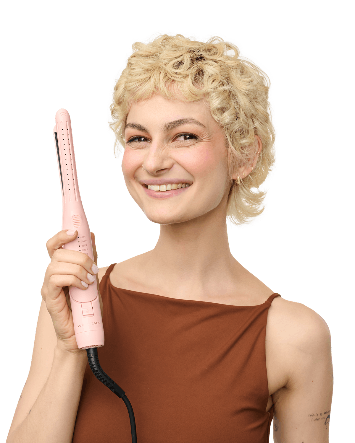 Woman with styled hair holding a pink hair straightener against a black background