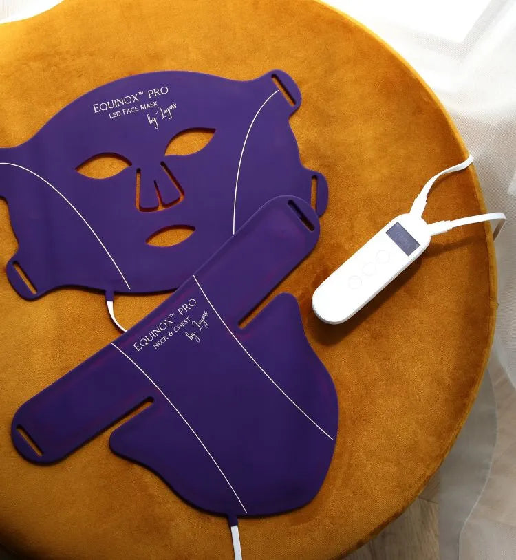Equinox Pro LED face and neck masks laid on a table with the controller, showing the purple silicone design