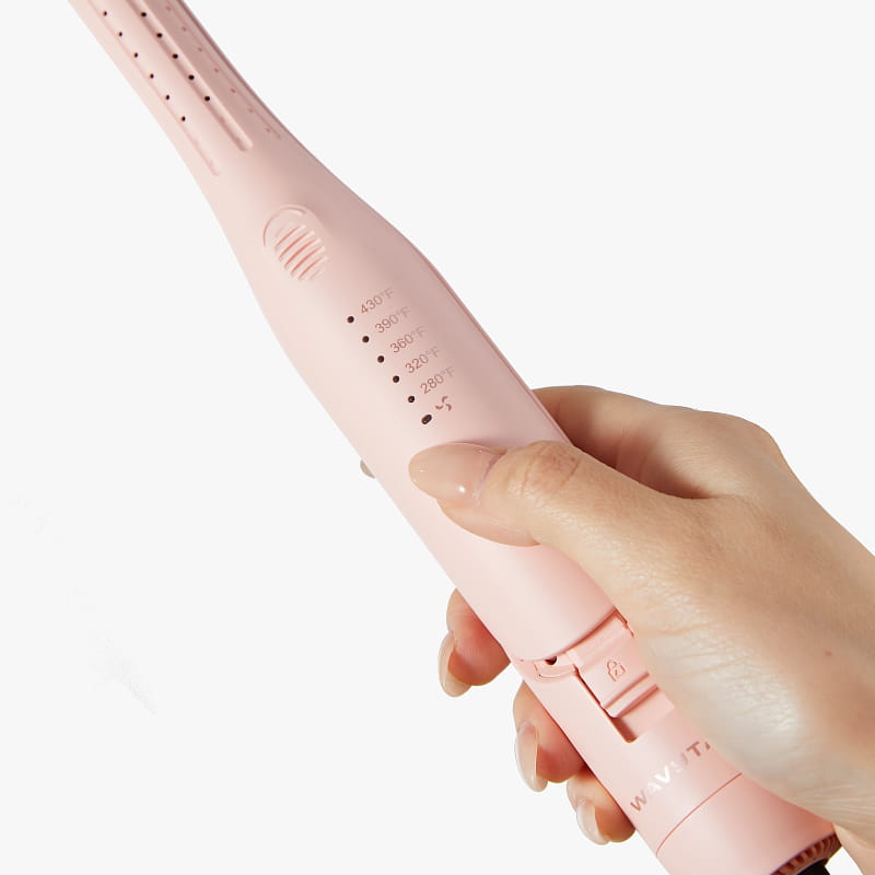 Pink hair straightener held in a hand against a white background