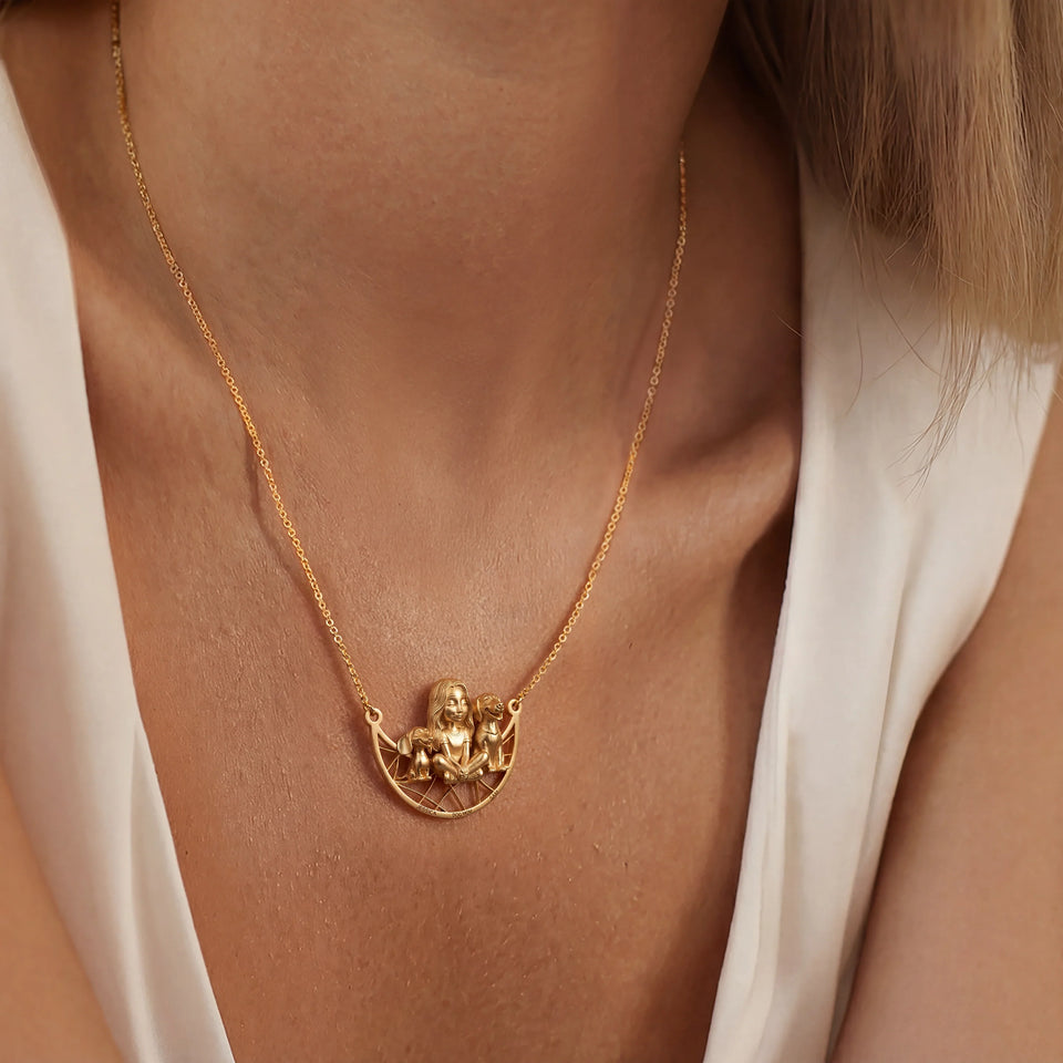 Gold necklace with a dog pendant on a person wearing a white top.